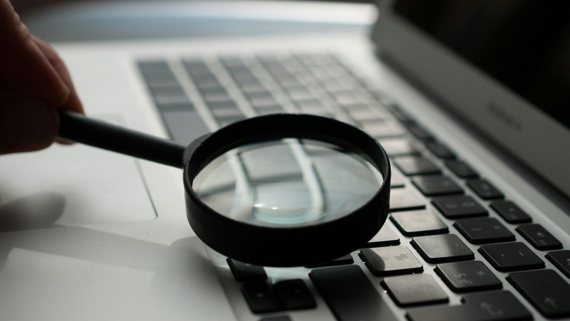 magnifying glass near gray laptop computer